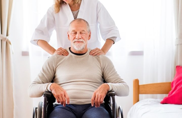 Eine Person gibt einer anderen im Rollstuhl eine entspannende Massage.