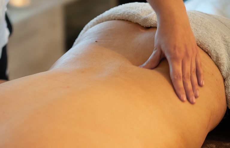 Massierende Hände berühren punktuell den Rücken einer entspannten Person.